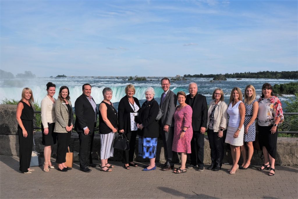 The Lieutenant Governor stands in front of Niagara Falls with a large number of the members of the Niagara Parks Commission and partner organizations