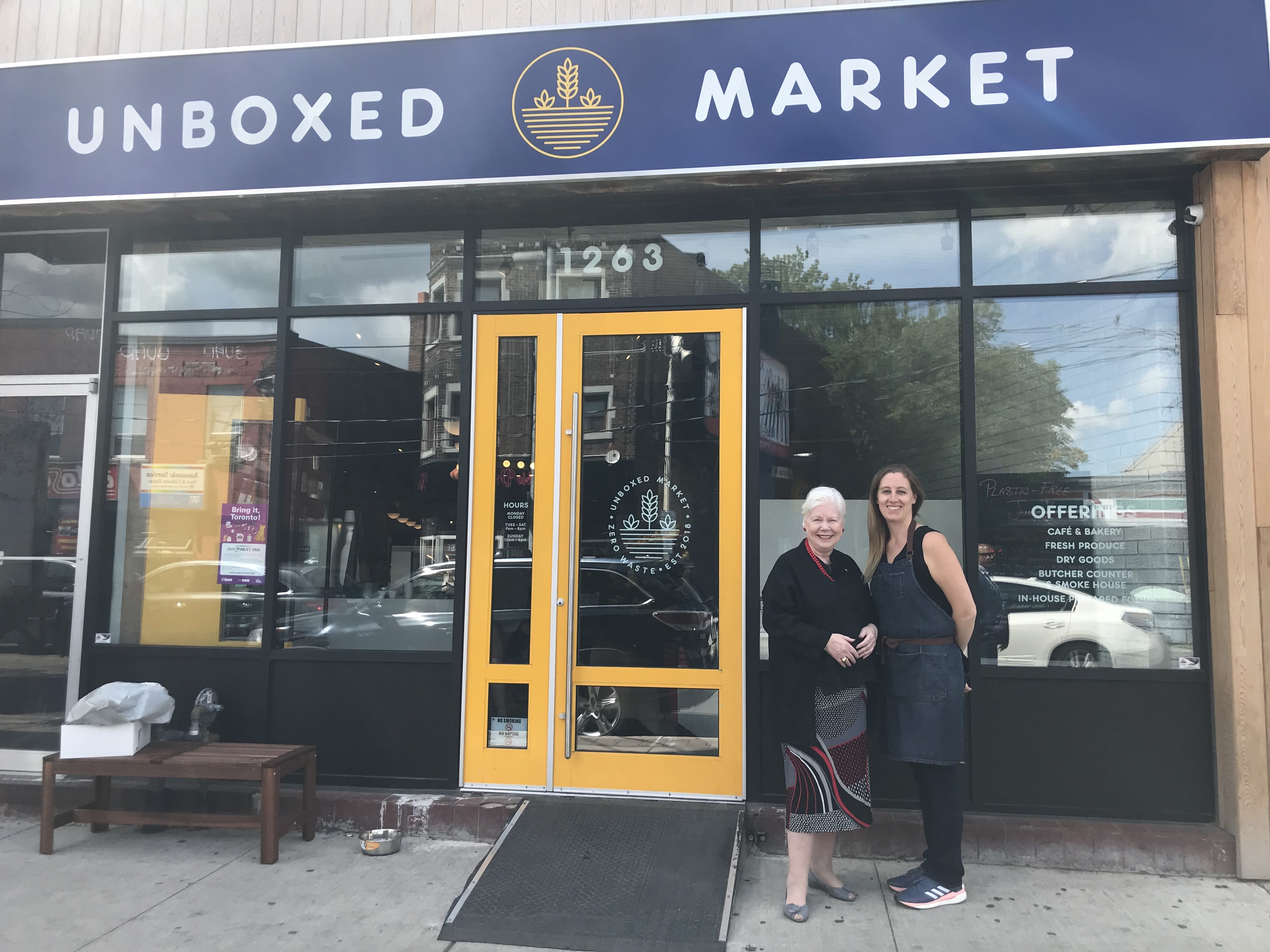 The Lieutenant Governor stands in front of the unboxed Market sign with the co-owner Michelle Genttner
